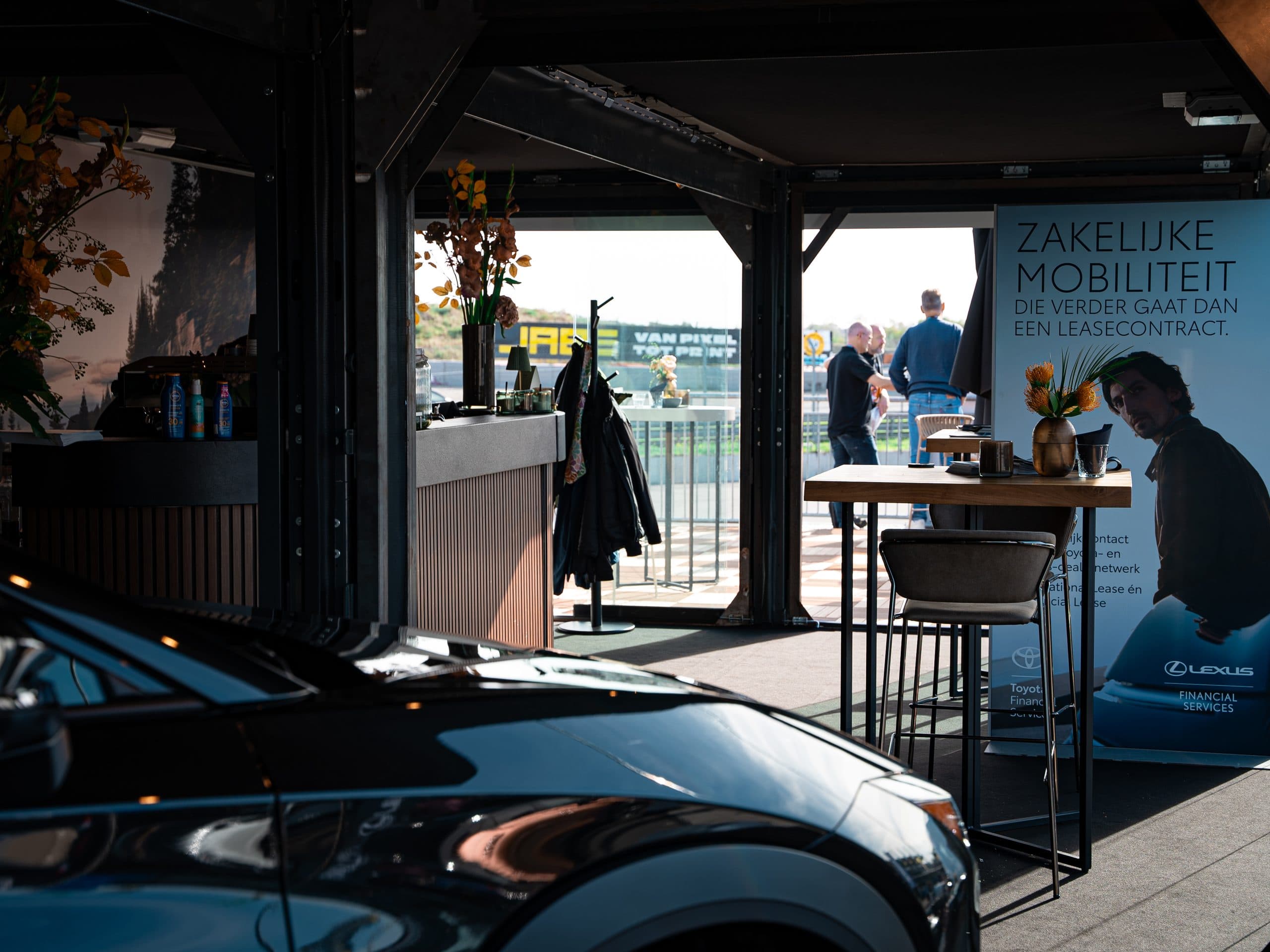 Binnenkant van een WEFOLDIT hospitality-unit met bar, statafels en open gevel naar het circuit